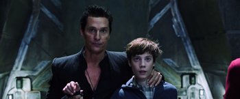 Movie still from “The Dark Tower” (2017), directed by Nikolaj Arcel – A man standing next to a young boy in a room; Medium shot, Low angle