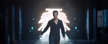 Movie still from “The Dark Tower” (2017), directed by Nikolaj Arcel – A man in a black suit walking in front of an illuminated wall; Medium shot, Low angle