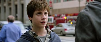 Movie still from “The Dark Tower” (2017), directed by Nikolaj Arcel – A young man standing on the side of the street; Close Up shot, Over the shoulder angle