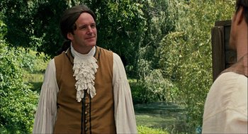 Movie still from “Choke” (2008), directed by Clark Gregg – A man wearing a brown vest and a white shirt; Medium shot, Over the shoulder angle