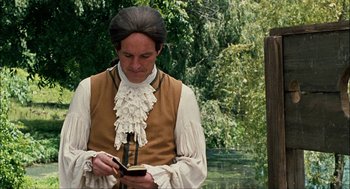 Movie still from “Choke” (2008), directed by Clark Gregg – A man in a period costume looking at his cell phone; Medium shot, Over the shoulder angle