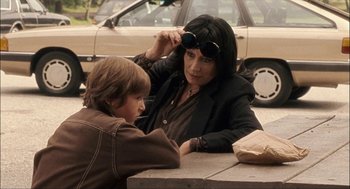 Movie still from “Choke” (2008), directed by Clark Gregg – A woman sitting at a table with a young boy; Medium shot, Over the shoulder angle