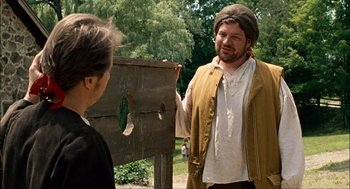 Movie still from “Choke” (2008), directed by Clark Gregg – A man wearing a hat talking to another man outside; Medium shot, Over the shoulder angle