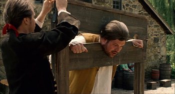 Movie still from “Choke” (2008), directed by Clark Gregg – A man being held down by a wooden cross; Medium shot, Over the shoulder angle