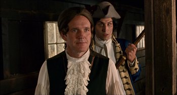 Movie still from “Choke” (2008), directed by Clark Gregg – A man in a pirate costume standing next to another man; Medium shot, Over the shoulder angle