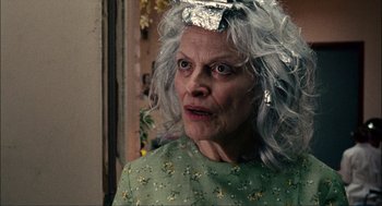 Movie still from “Choke” (2008), directed by Clark Gregg – An older woman with gray hair wearing a green dress; Close Up shot, Over the shoulder angle