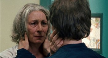 Movie still from “Choke” (2008), directed by Clark Gregg – An older woman looking in the mirror while holding her neck; Close Up shot, Over the shoulder angle