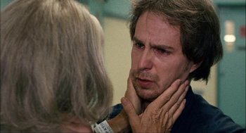 Movie still from “Choke” (2008), directed by Clark Gregg – A man with his hand on his face and a woman with her hand on his chin; Close Up shot, Over the shoulder angle