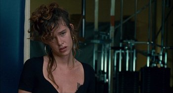 Movie still from “Choke” (2008), directed by Clark Gregg – A woman with a messy hair style looking at the camera; Close Up shot, Over the shoulder angle