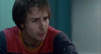 Movie still from “Choke” (2008), directed by Clark Gregg – A person sitting down looking at something; Close Up shot, Over the shoulder angle