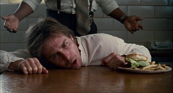 Movie still from “Choke” (2008), directed by Clark Gregg – A man laying on a table with a sandwich in front of him; Close Up shot, High angle