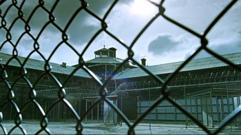 Movie still from “Chopper” (2000), directed by Andrew Dominik – A jail cell with a clock tower in the background; Extreme Wide shot, Low angle