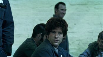 Movie still from “Chopper” (2000), directed by Andrew Dominik – A man with a red hair wig is smiling for the camera; Close Up shot, Over the shoulder angle