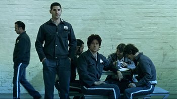 Movie still from “Chopper” (2000), directed by Andrew Dominik – A group of people sitting in a room; Medium shot, High angle