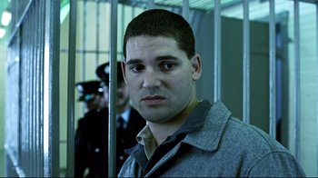 Movie still from “Chopper” (2000), directed by Andrew Dominik – A man standing in front of a jail cell; Close Up shot, Low angle
