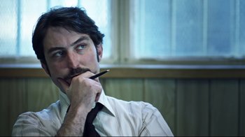 Movie still from “Chopper” (2000), directed by Andrew Dominik – A person holding a pen to his mouth; Close Up shot, Over the shoulder angle