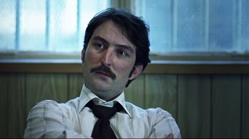 Movie still from “Chopper” (2000), directed by Andrew Dominik – A man in a white shirt and a brown neck tie; Close Up shot, Low angle