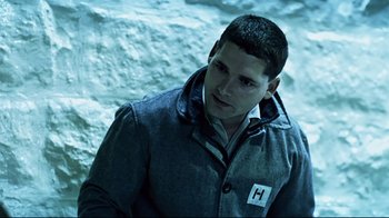 Movie still from “Chopper” (2000), directed by Andrew Dominik – A man wearing a jacket standing next to a wall; Medium shot, High angle