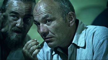 Movie still from “Chopper” (2000), directed by Andrew Dominik – A man sitting down with a cigarette in his mouth; Close Up shot, Low angle