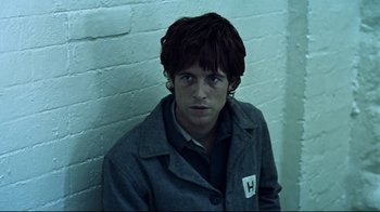 Movie still from “Chopper” (2000), directed by Andrew Dominik – A young man in a gray jacket is posing for a picture; Close Up shot, High angle