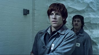 Movie still from “Chopper” (2000), directed by Andrew Dominik – A man in a gray jacket and a man in a brown jacket; Medium shot, Low angle