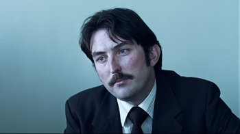 Movie still from “Chopper” (2000), directed by Andrew Dominik – A person wearing a suit and tie; Close Up shot, Low angle