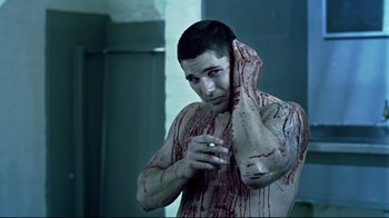 Movie still from “Chopper” (2000), directed by Andrew Dominik – A man with blood all over his face and body; Medium shot, High angle