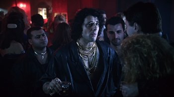 Movie still from “Chopper” (2000), directed by Andrew Dominik – A group of people standing around a room; Medium shot, Over the shoulder angle