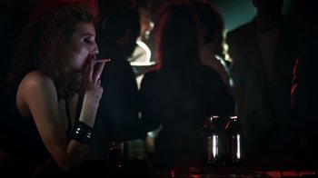 Movie still from “Chopper” (2000), directed by Andrew Dominik – A woman smoking a cigarette in front of a group of people; Medium shot, Low angle