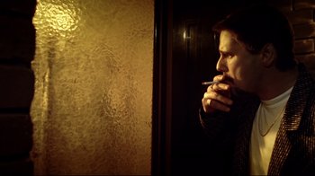 Movie still from “Chopper” (2000), directed by Andrew Dominik – A man smoking a cigarette while looking out of a window; Close Up shot, Low angle