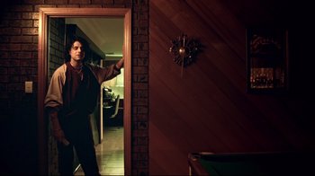 Movie still from “Chopper” (2000), directed by Andrew Dominik – A man standing next to a wall in a room; Medium shot, Low angle