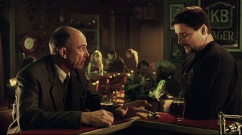 Movie still from “Chopper” (2000), directed by Andrew Dominik – A man sitting at a table in a restaurant with another man; Medium shot, Over the shoulder angle