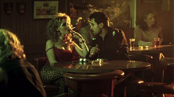 Movie still from “Chopper” (2000), directed by Andrew Dominik – A man and a woman sitting at a table smoking cigarettes; Medium shot, Over the shoulder angle