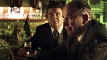 Movie still from “Chopper” (2000), directed by Andrew Dominik – Two men sitting at a table in front of drinks; Close Up shot, Over the shoulder angle