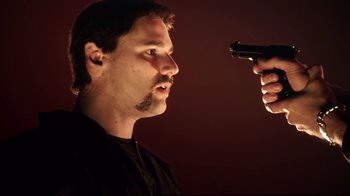 Movie still from “Chopper” (2000), directed by Andrew Dominik – A man is holding a gun up to his face; Close Up shot, Low angle
