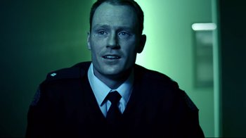 Movie still from “Chopper” (2000), directed by Andrew Dominik – A man wearing a suit and tie in front of a green background; Close Up shot, Over the shoulder angle