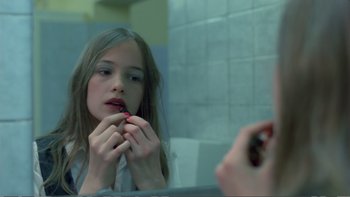 Movie still from “Christiane F.” (1981), directed by Uli Edel – A woman is looking in the mirror and putting lipstick on; Close Up shot, Over the shoulder angle