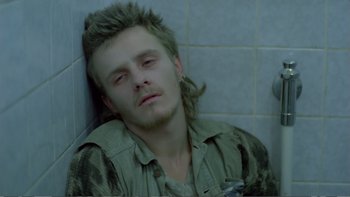 Movie still from “Christiane F.” (1981), directed by Uli Edel – A young man with long hair is laying on the floor; Close Up shot, High angle