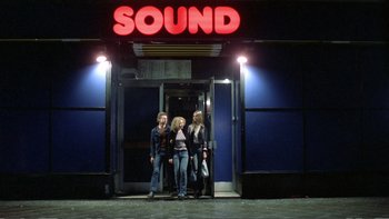 Movie still from “Christiane F.” (1981), directed by Uli Edel – Two women standing in front of a building at night; Wide shot, Low angle