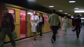 Movie still from “Christiane F.” (1981), directed by Uli Edel – A woman in a white coat walking down a train platform; Wide shot, Low angle