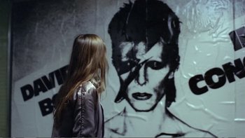 Movie still from “Christiane F.” (1981), directed by Uli Edel – A woman standing in front of a wall with a picture of a man; Close Up shot, Over the shoulder angle