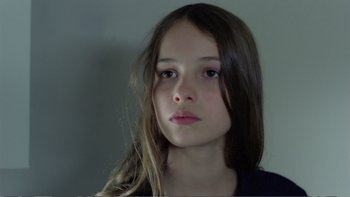 Movie still from “Christiane F.” (1981), directed by Uli Edel – A young girl with long brown hair looking at the camera; Close Up shot, Low angle