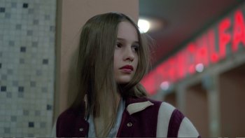 Movie still from “Christiane F.” (1981), directed by Uli Edel – A girl with long hair is standing by a wall; Close Up shot, Low angle