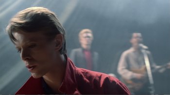 Movie still from “Christiane F.” (1981), directed by Uli Edel – A man in a red shirt and two other men in a black suit; Close Up shot, Over the shoulder angle