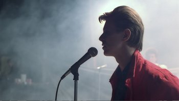 Movie still from “Christiane F.” (1981), directed by Uli Edel – A man is speaking into a microphone in the dark; Medium shot, Low angle