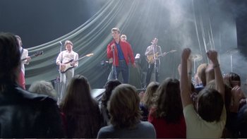 Movie still from “Christiane F.” (1981), directed by Uli Edel – A group of people on a stage singing and playing instruments; Wide shot, High angle
