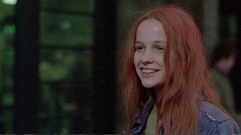 Movie still from “Christiane F.” (1981), directed by Uli Edel – A girl with red hair smiling for the camera; Close Up shot, Low angle