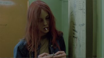 Movie still from “Christiane F.” (1981), directed by Uli Edel – A woman with red hair is smoking a cigarette; Close Up shot, Over the shoulder angle