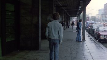 Movie still from “Christiane F.” (1981), directed by Uli Edel – A man walking down a sidewalk in a building; Wide shot, Over the shoulder angle