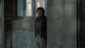 Movie still from “Christiane F.” (1981), directed by Uli Edel – A man leaning against a wall with his hands in his pockets; Medium shot, Over the shoulder angle